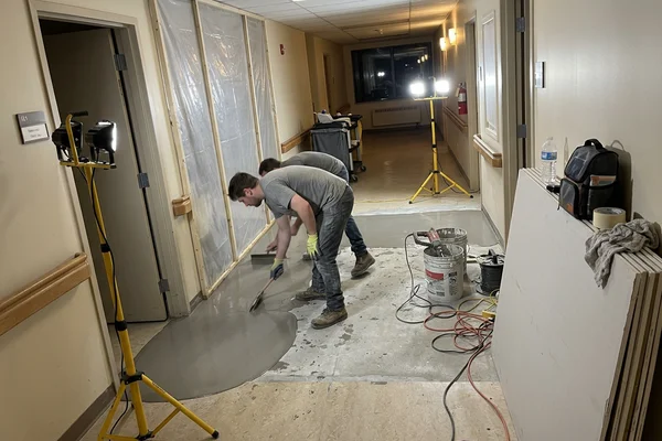 Crew running self-levelling underlayment in a long-term care facility at night