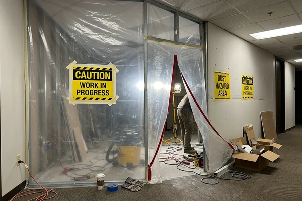 Hoarded work zone with dust containment inside an occupied building during a night shift