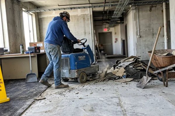 Old commercial floor being stripped back to slab with a ride-on removal machine