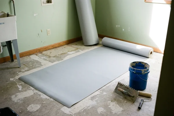 Roll of homogeneous sheet vinyl part unrolled across a prepared clinic floor