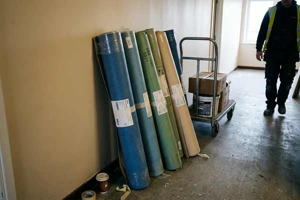 Rolls of natural linoleum in several colours standing in a prepared institutional corridor