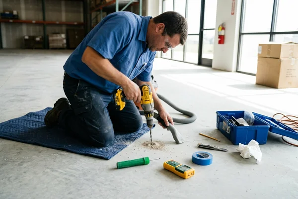 Technician drilling an in-situ relative humidity probe hole for ASTM F2170 testing