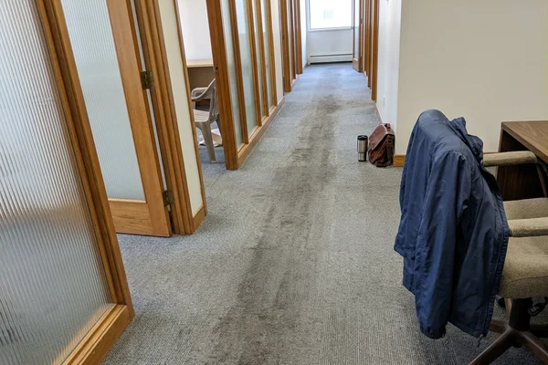 Worn carpet tile traffic lane in an office corridor before replacement