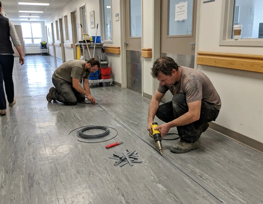 Installers heat welding a homogeneous sheet vinyl seam in a GTA healthcare corridor